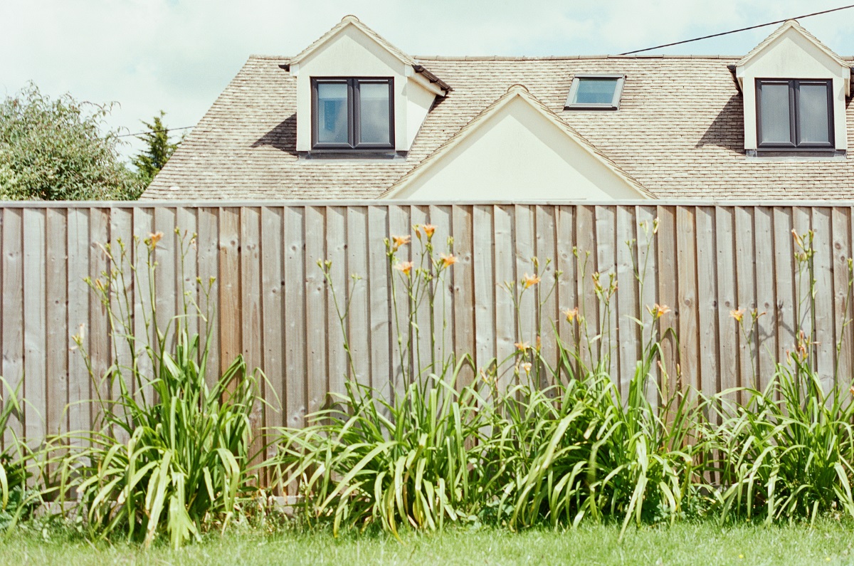 wooden fence, with a house in the background